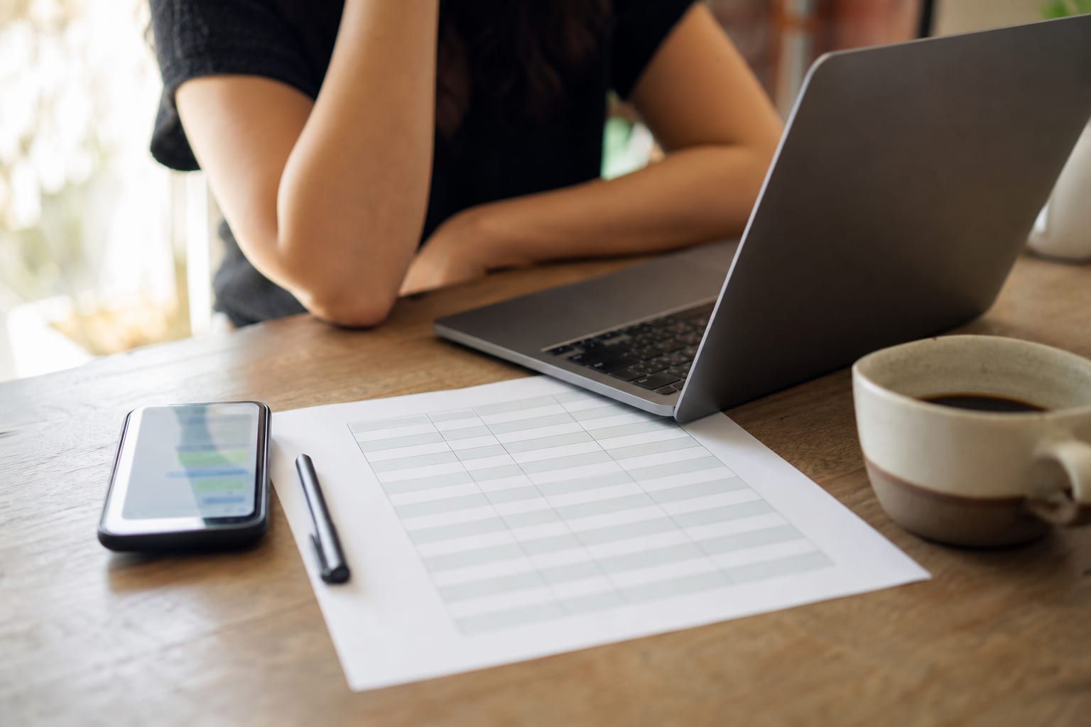 Mesa de trabalho com celular, folha impressa e notebook representando as três formas de organizar a escala